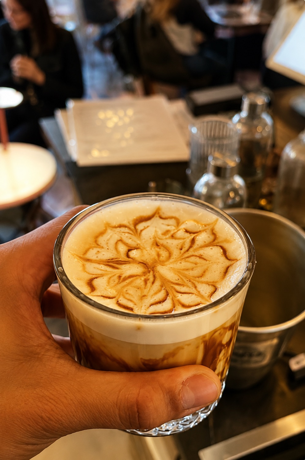 Latte glacé avec dessin en mousse tenu au comptoir